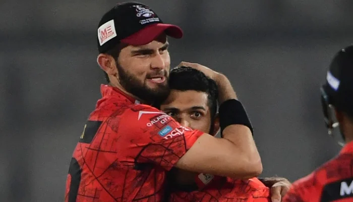 A Lahore Qalandars cricketer in uniform walking off the field, looking serious, with the team logo visible